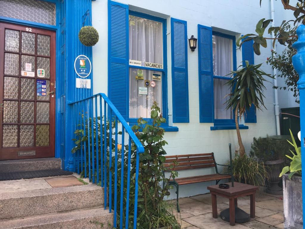 ein blau-weißes Haus mit einer Bank davor in der Unterkunft Avoca Villa Guest House in Saint Helier Jersey