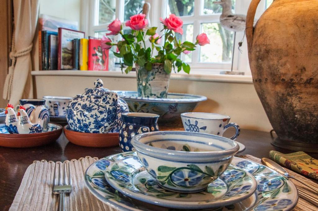 een tafel met blauwe en witte kopjes en borden en bloemen bij Milton Farm in East Knoyle