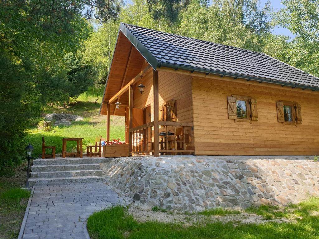 una cabaña de madera con una pasarela de piedra delante de ella en Domki letniskowe Pod Lasem en Koziniec