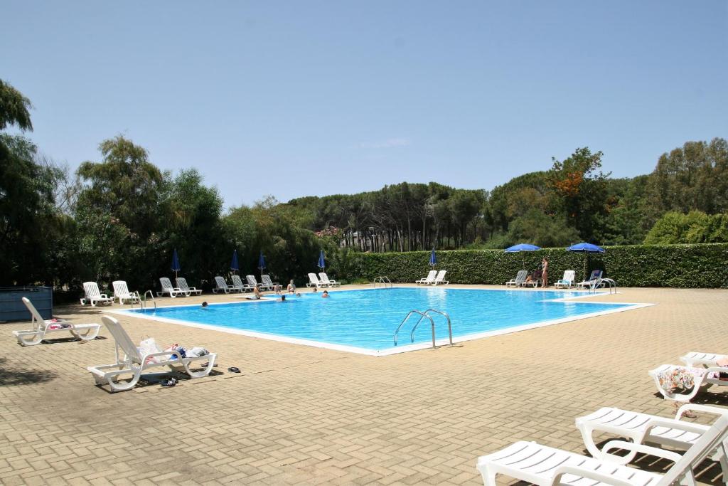 una gran piscina con sillas y gente sentada a su alrededor en Portoada Park Villas, en Pizzo