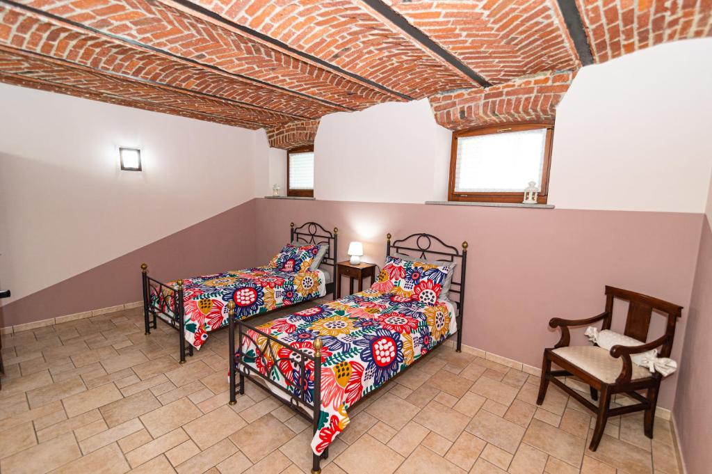 1 dormitorio con 2 camas y 1 silla en OstellOrto en San Martino Canavese