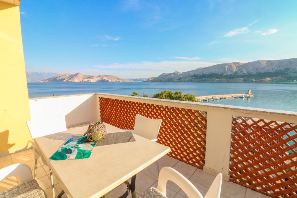a table and chairs on a balcony with a view of the water at Apartments Ines in Baška