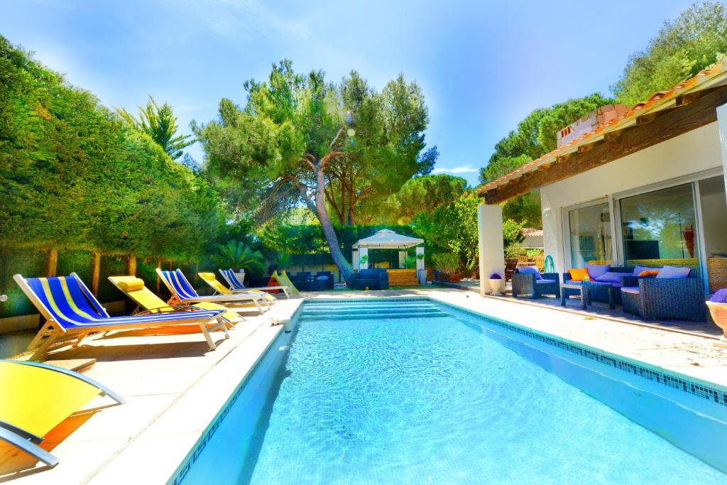 een zwembad met ligstoelen en een huis bij Villa Aurelie in Cap d'Agde