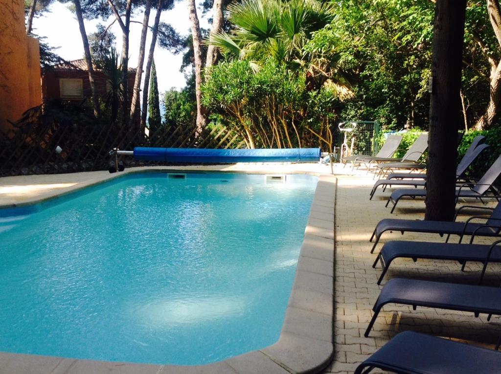 une grande piscine avec des chaises et des arbres dans l'établissement 50m Plage T2 Grande Terrasse Vue Mer Climatisé Piscine Chauffée, Parking clos gratuit, à Sanary-sur-Mer