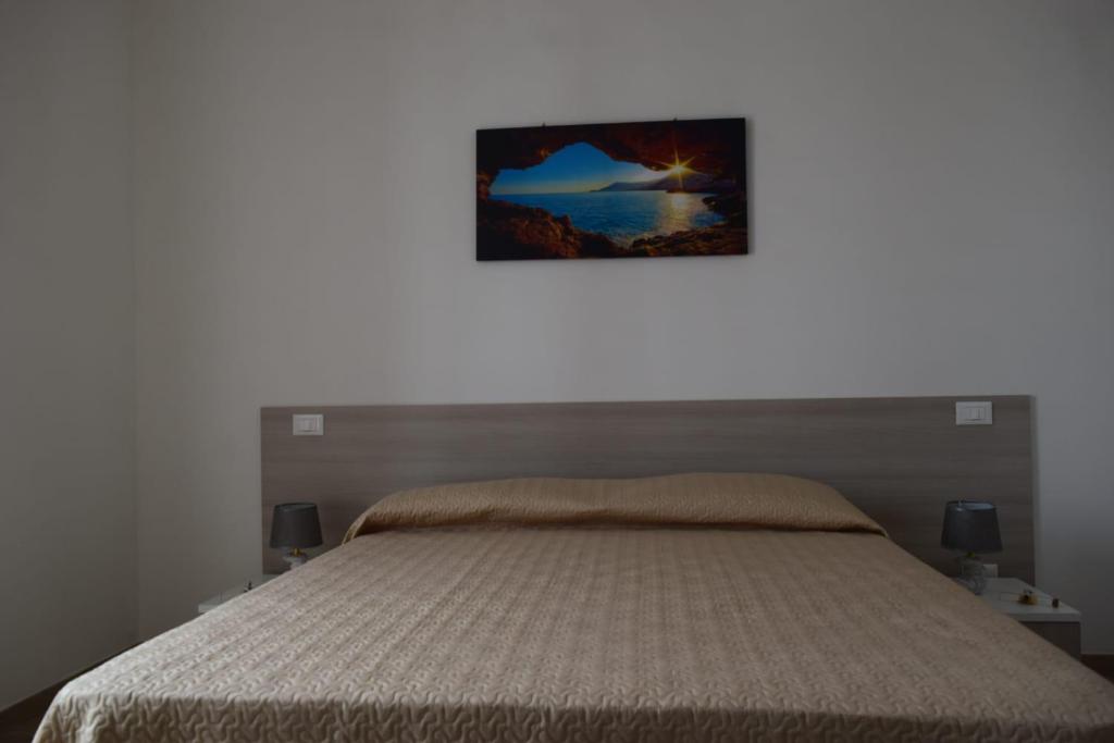 a bedroom with a bed with a picture on the wall at Acqua Chiara Appartamenti in San Vito lo Capo