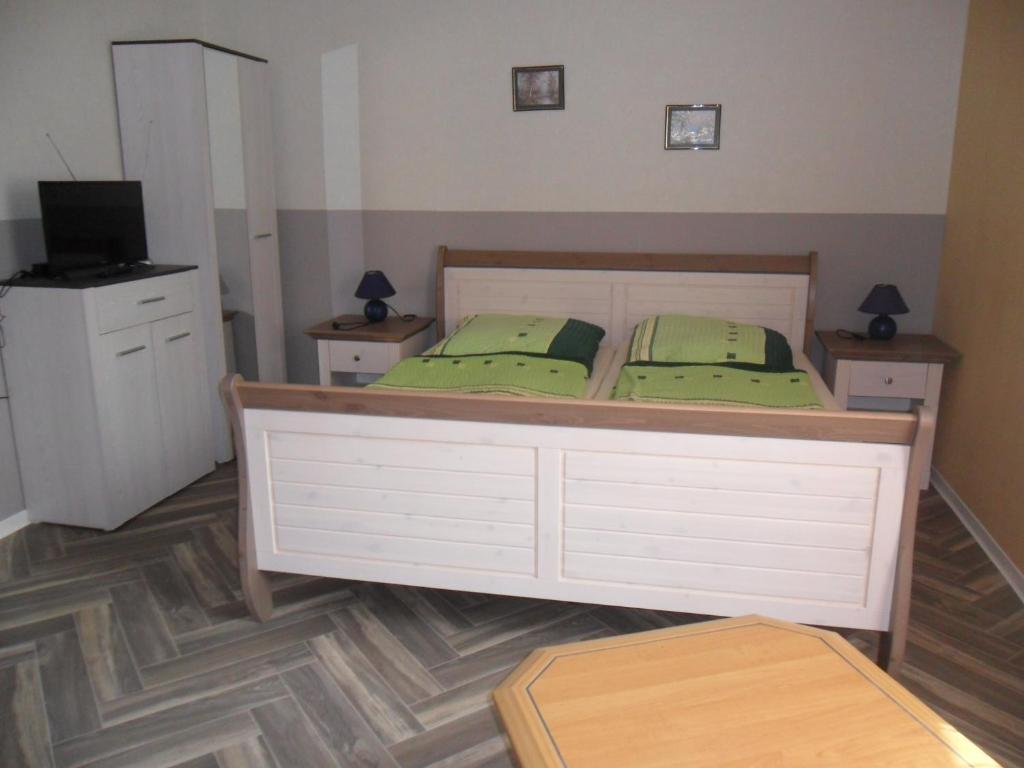 1 dormitorio con 1 cama con almohadas verdes y TV en Pension Sabine, en Ummanz