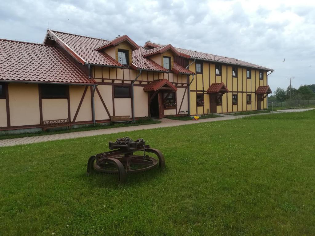 a house with a hose laying in the grass at Pensjonat Przy Stajni in Kierzkowo