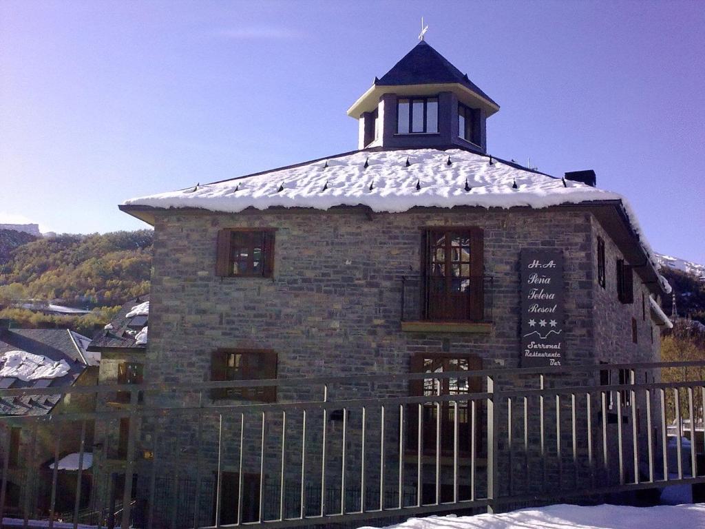 un pequeño edificio de ladrillo con una torre en la parte superior en Aparthotel Peña Telera Resort, en El Pueyo de Jaca