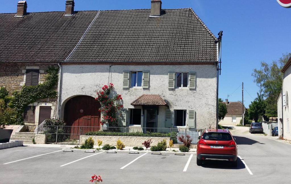 une voiture rouge garée dans un parking en face d'une maison dans l'établissement La roseraie de Camille, à Mont-sous-Vaudrey