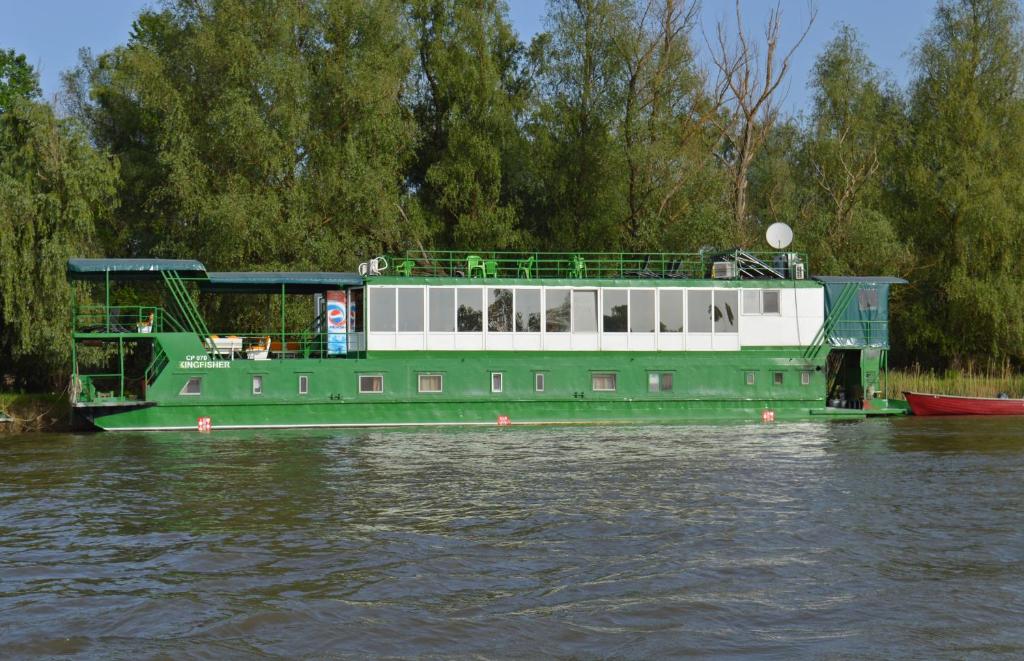Hotel Plutitor Kingfisher في Uzlina: قارب اخضر وابيض على الماء