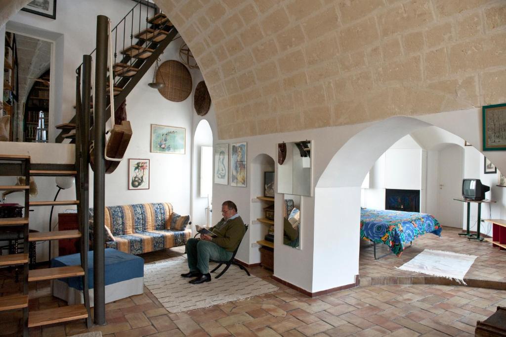 a man sitting on a couch in a living room at B&B En Suite in Matera