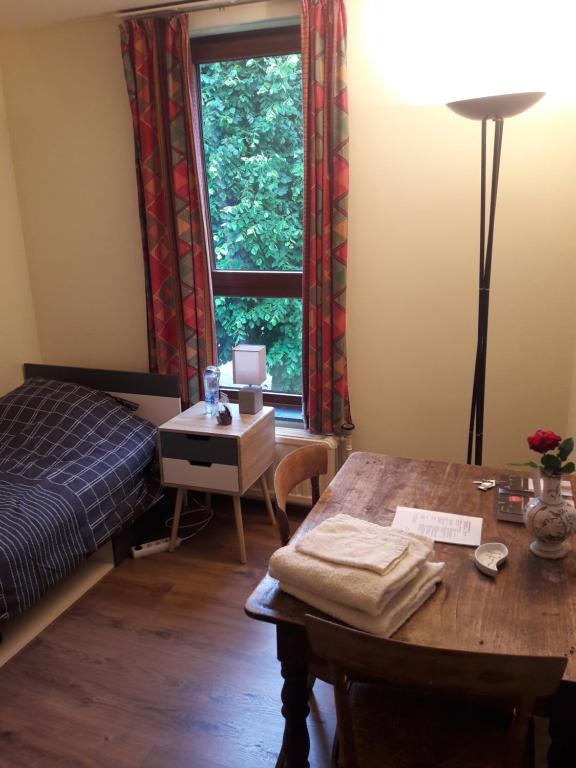 a bedroom with a table and a bed and a window at Chez Mimi - chambre vue parc in Brussels