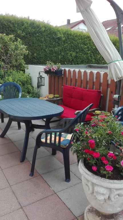 a patio with a table and a couch and flowers at Ferienwohnung nahe Ulm/Laupheim in Laupheim