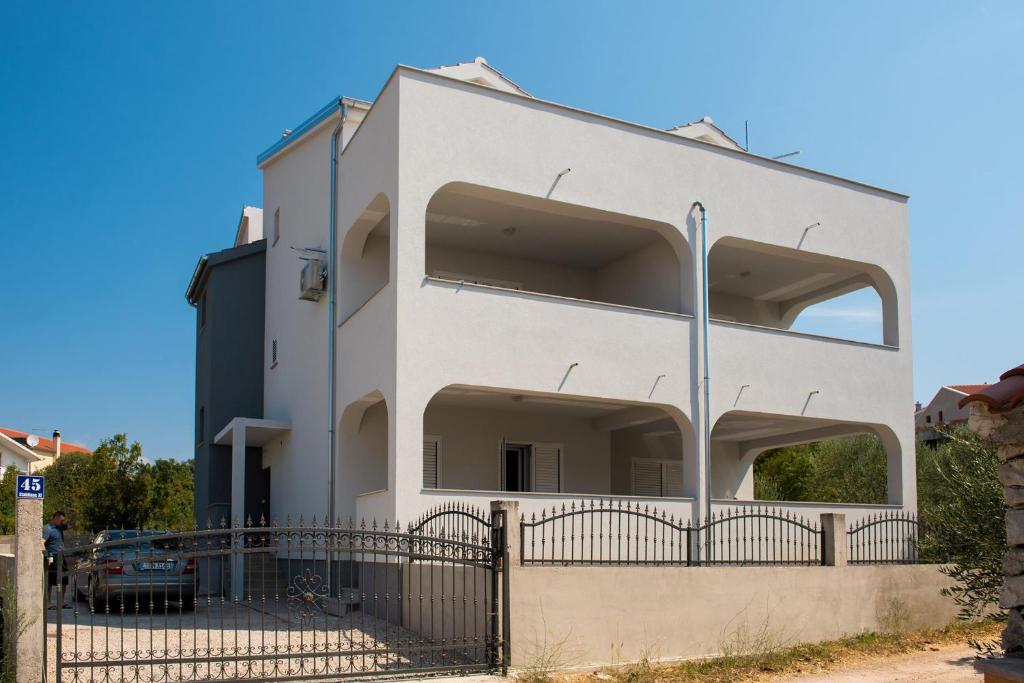 a white building with a fence in front of it at Apartment Vodice - Lovric in Vodice
