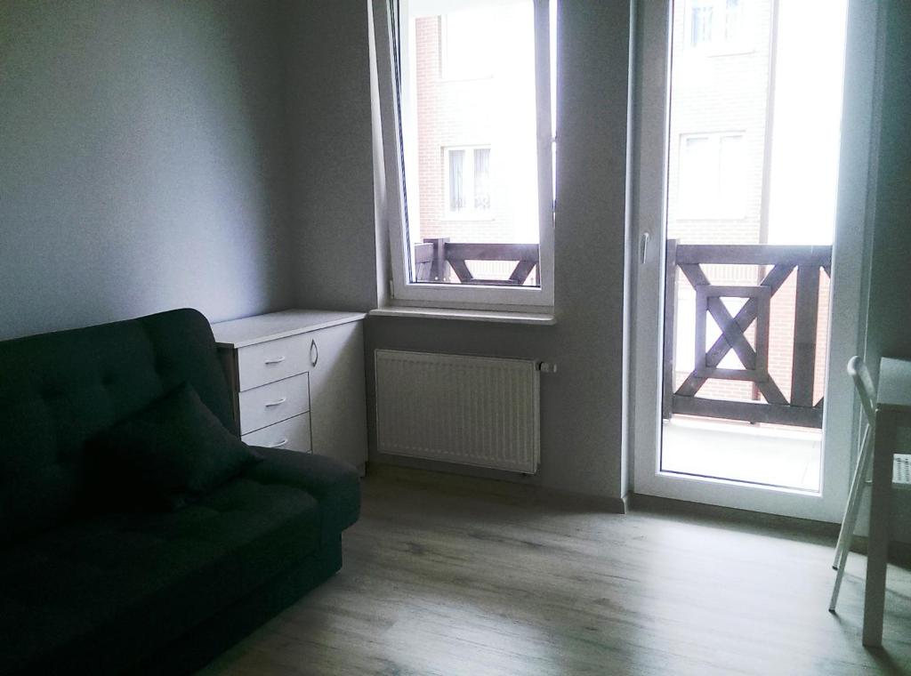 salon z kanapą i dwoma oknami w obiekcie Apartament Baltic w Sztutowie