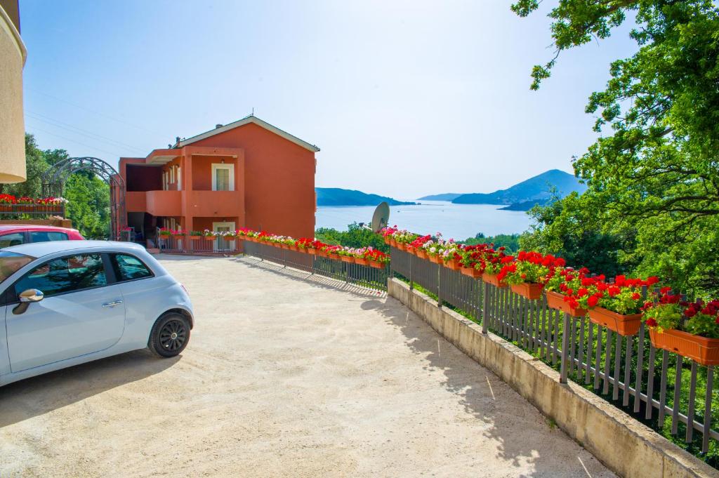 a white car parked next to a fence with flowers at Alessandra Apartments in Sveti Stefan
