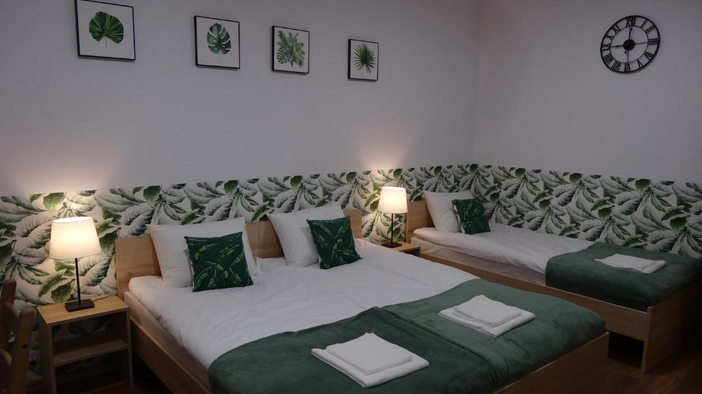 sypialnia z 2 łóżkami i zegarem na ścianie w obiekcie Villa Magnolia w Oświęcimiu