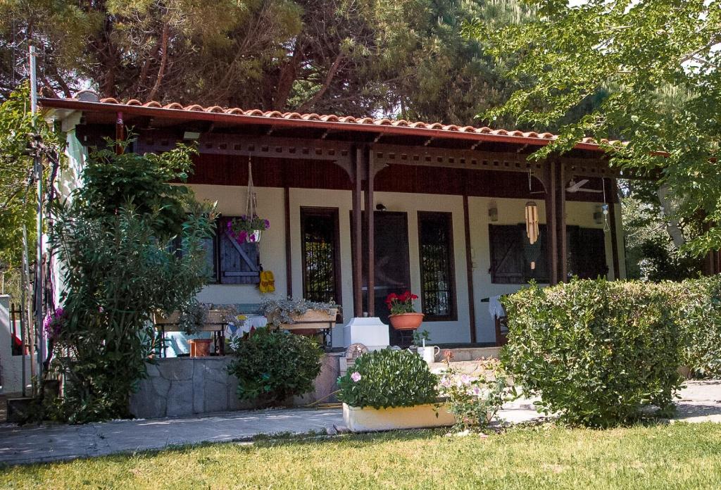 uma pequena casa branca com um alpendre e alguns arbustos em Estate Irene em Alexandroúpolis