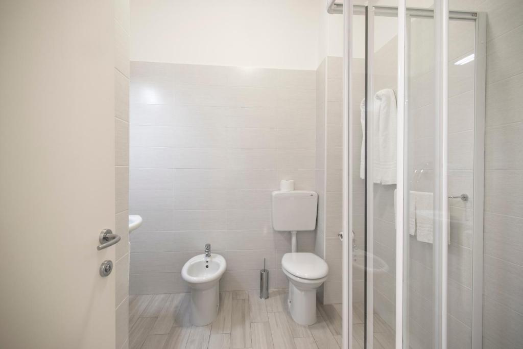 a white bathroom with a toilet and a shower at Hotel Continental in Caorle