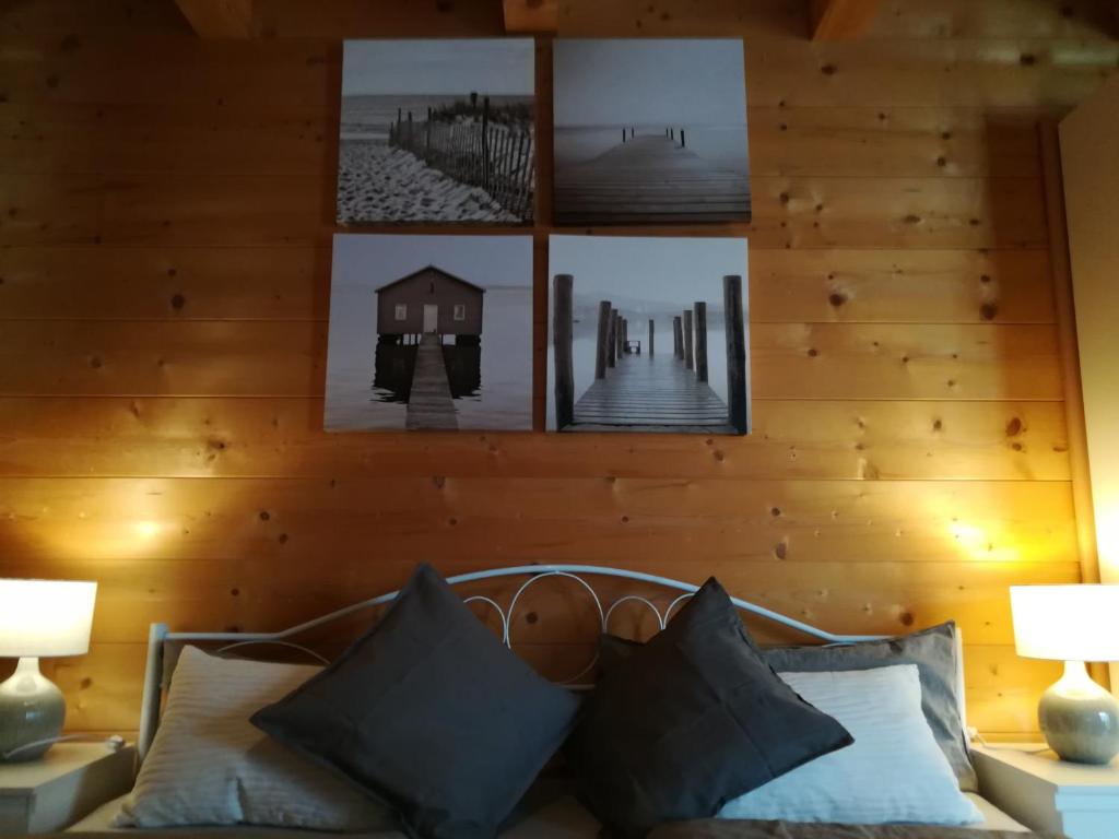 Studio im Blockhaus am Chiemsee في بيرناو آم شيمسي: غرفة بجدار خشبي مع صور فوق أريكة