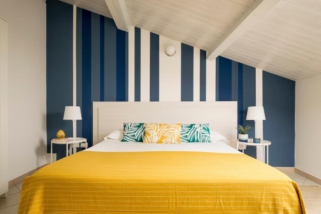 Un dormitorio con una cama amarilla con rayas azules y blancas en Civico 64 Bed & Breakfast in mansarda, en Palmi