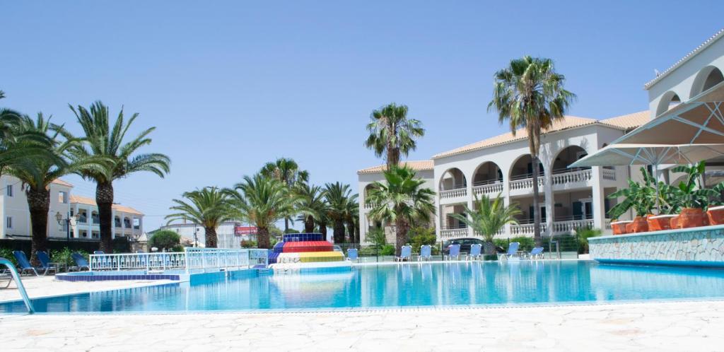 una gran piscina con palmeras y un edificio en Olympia en Laganas