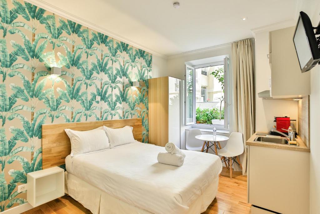 ein Schlafzimmer mit einem großen Bett und einer tropischen Tapete in der Unterkunft Nice Home - Studios Lido in Nizza