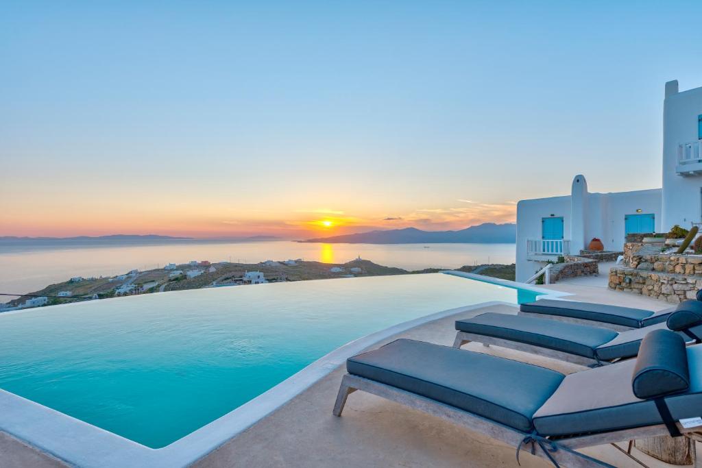 a pool with chairs and a sunset in the background at Mermaid Luxury Villas - Aquata Private pool in Fanari