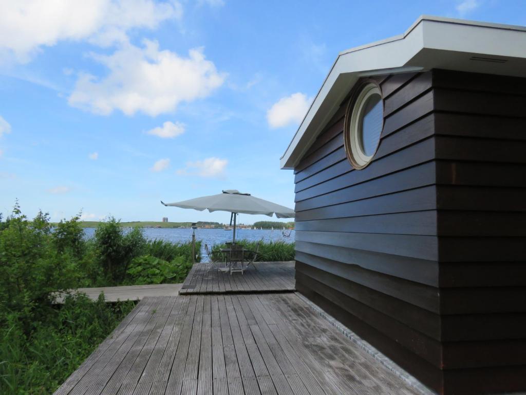 una terrazza in legno con tavolo e ombrellone di Vakantiehuis aan De Mooie Nel a Spaarndam