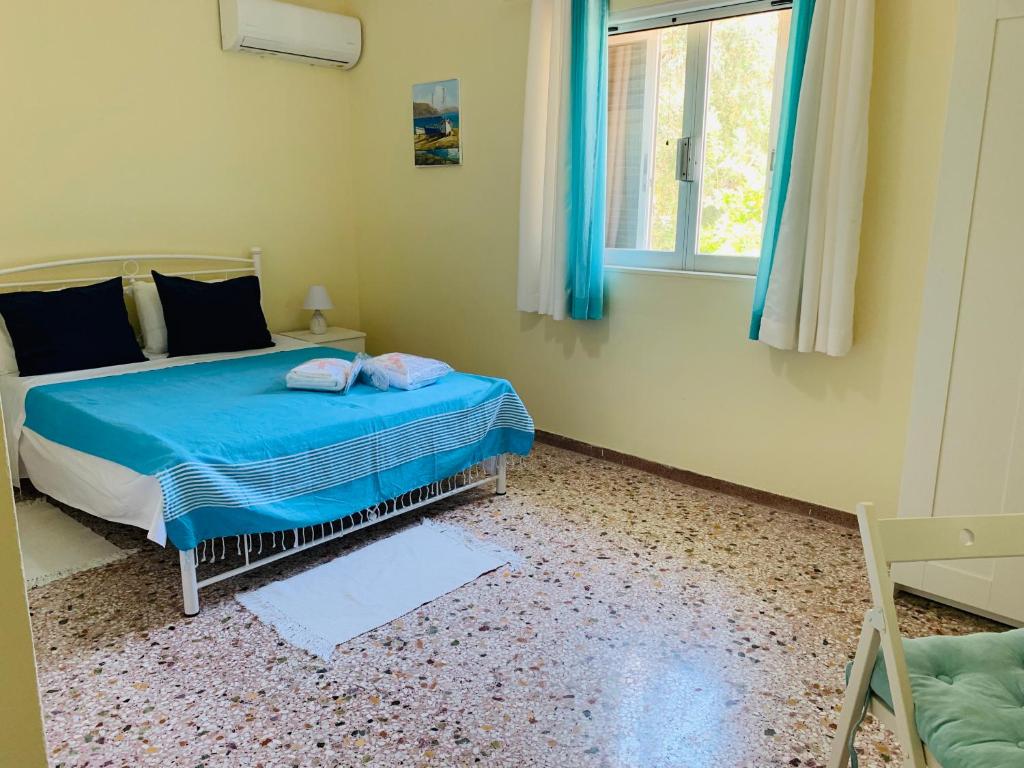 sypialnia z łóżkiem z niebieską pościelą i oknem w obiekcie Small Apartment in Markopoulo center w mieście Markopoulo Mesogaias