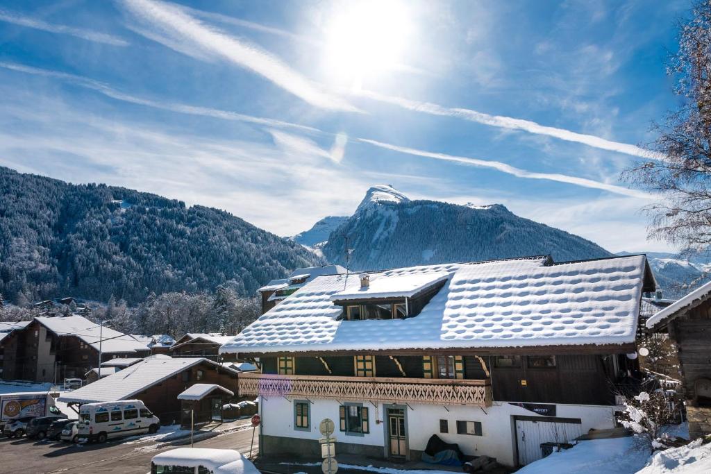 Nant Morzine في مورزين: منزل مغطى بالثلج مع جبل في الخلفية