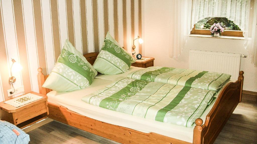 een bed met groene en witte lakens en kussens bij Mosel-Ferienwohnung Berhard in Bruttig-Fankel