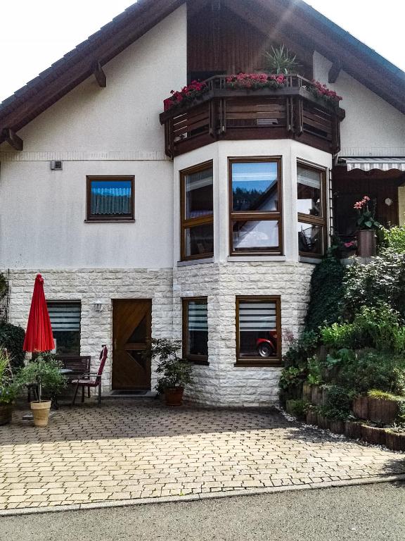 a house with a balcony and a red umbrella at Mosel-Ferienwohnung Berhard in Bruttig-Fankel