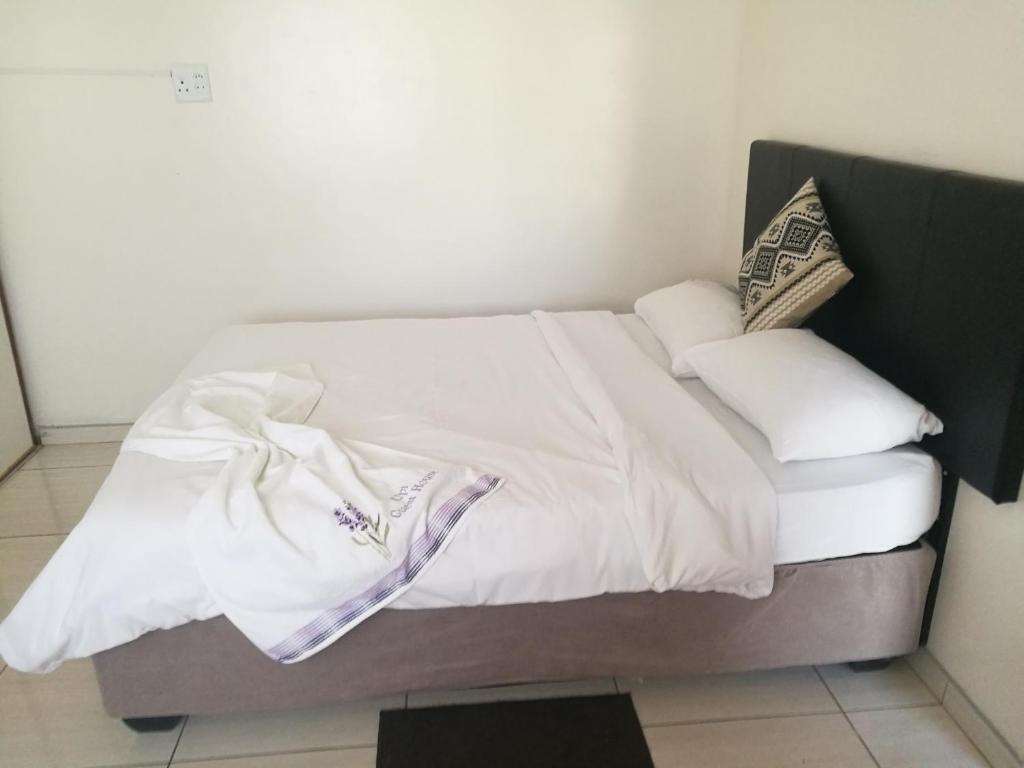 a bed with white sheets and pillows on it at Upi guesthouse in Otjiwarongo