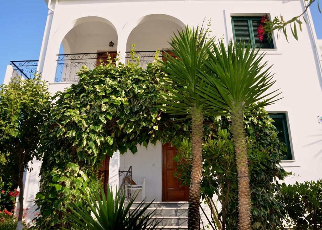 a white house with palm trees in front of it at Kostas' Garden in Roda