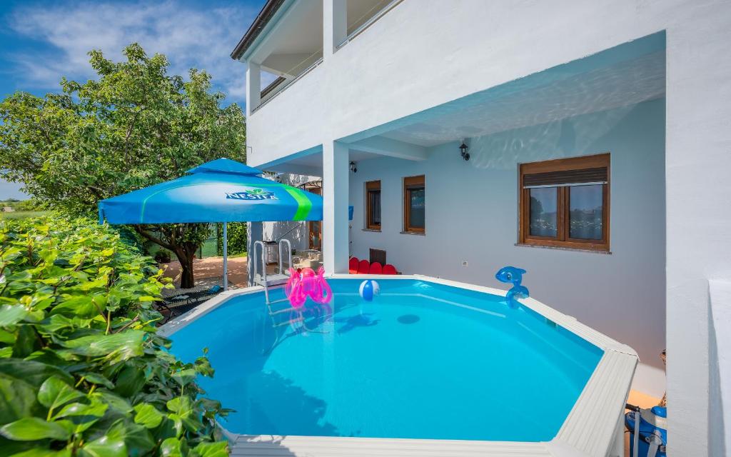 einen Pool mit Sonnenschirm neben einem Haus in der Unterkunft Apartman Summer Breeze in Marčana