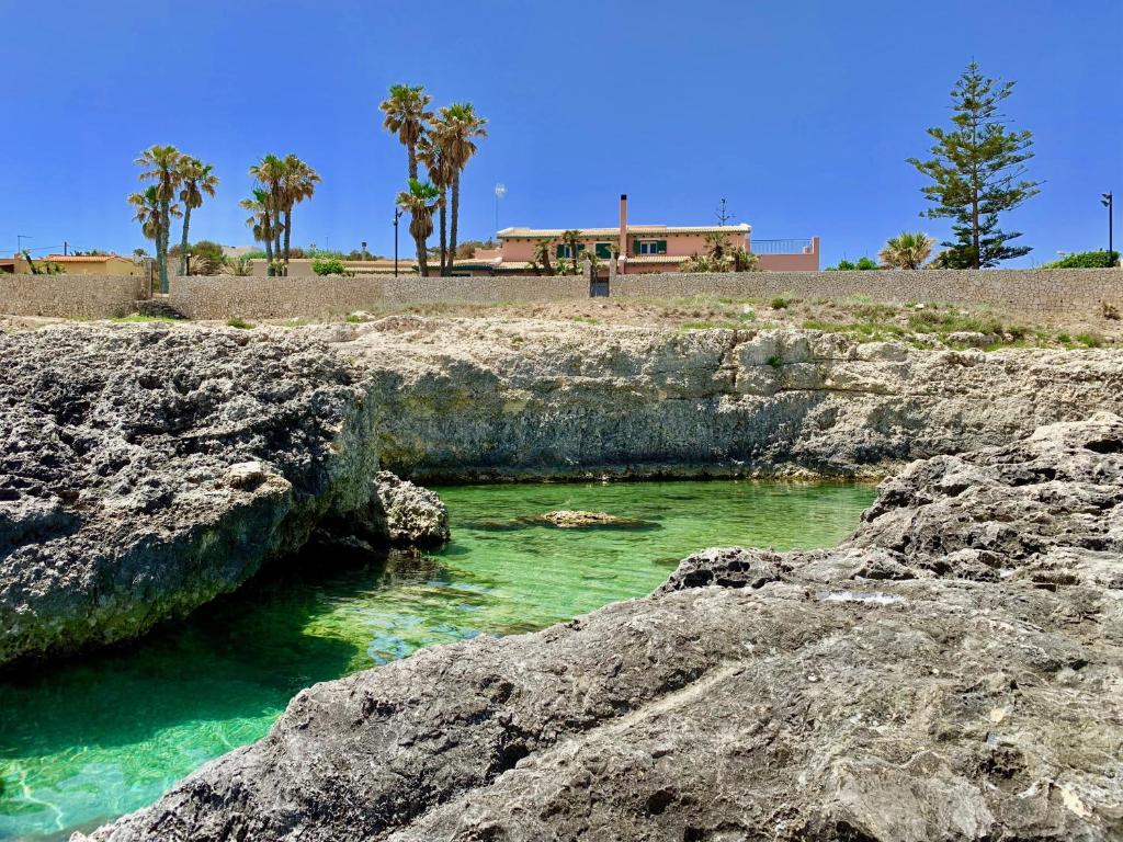 una piscina di acqua verde smeraldo su una spiaggia rocciosa di Villa Sara Costa Pergola ad Augusta