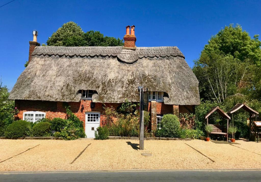 a large brick house with a thatched roof at Thatched Cottage Hotel in Brockenhurst