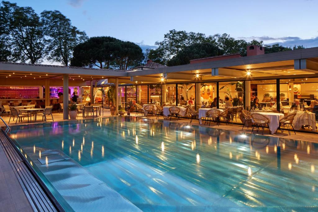 a swimming pool with tables and chairs in a building at Villa Duflot Hôtel & Spa Perpignan in Perpignan