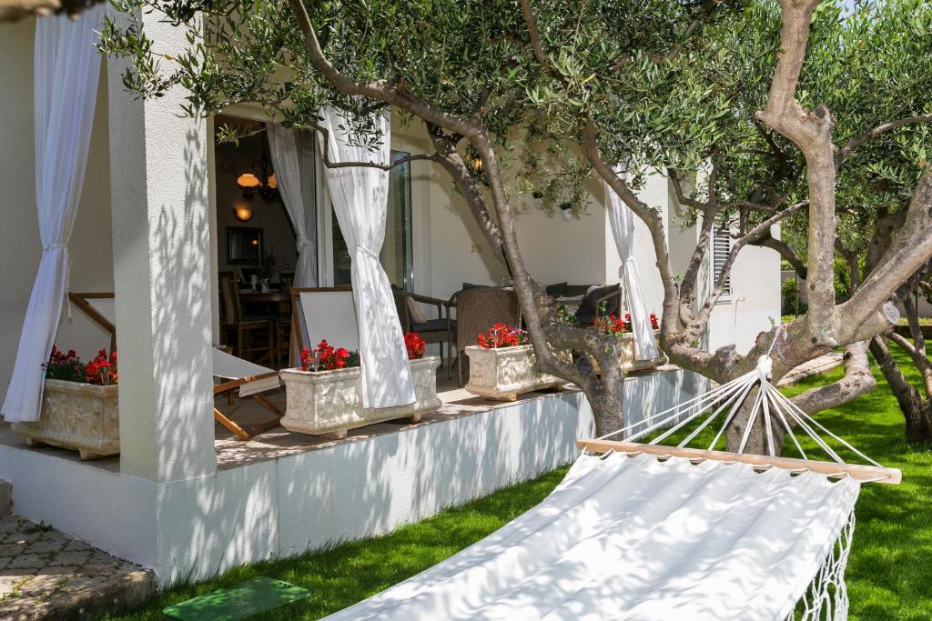 a hammock in front of a house with trees at Villa Boško in Kaštela