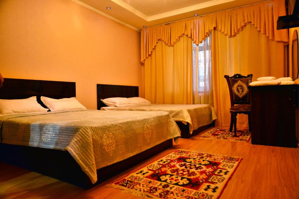 a bedroom with two beds and a chair at Astoria B&B in Osh