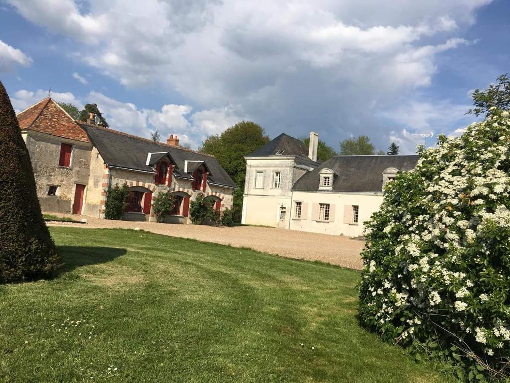 uma grande casa branca e um quintal com flores em Gîte de Bel air em Villeloin-Coulangé