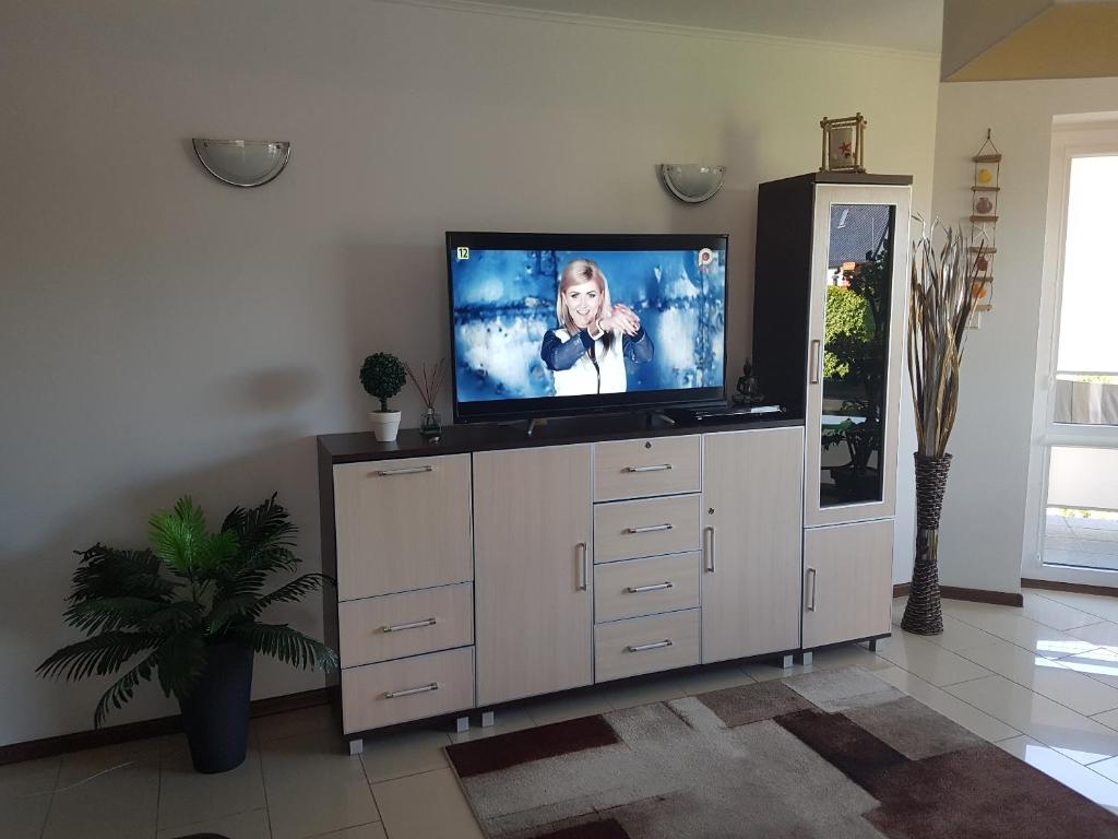 a living room with a flat screen tv on a cabinet at Apartament z basenem do 8 miejsc noclegowych in Ustronie Morskie
