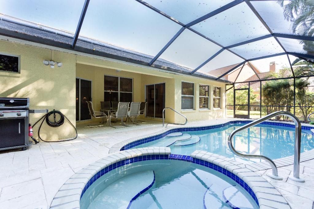 uma piscina interior com um grande telhado de vidro em Serene & Attractive Heated Pool Spa Home em Estero