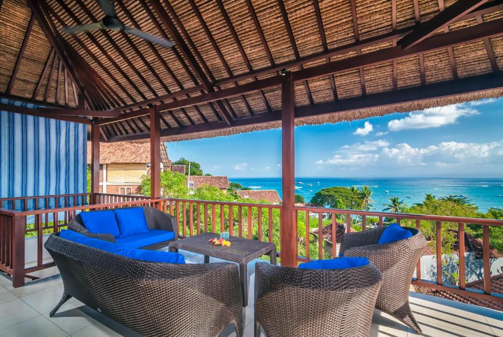 um pátio com cadeiras e uma mesa e o oceano em Villa Keluarga em Nusa Lembongan
