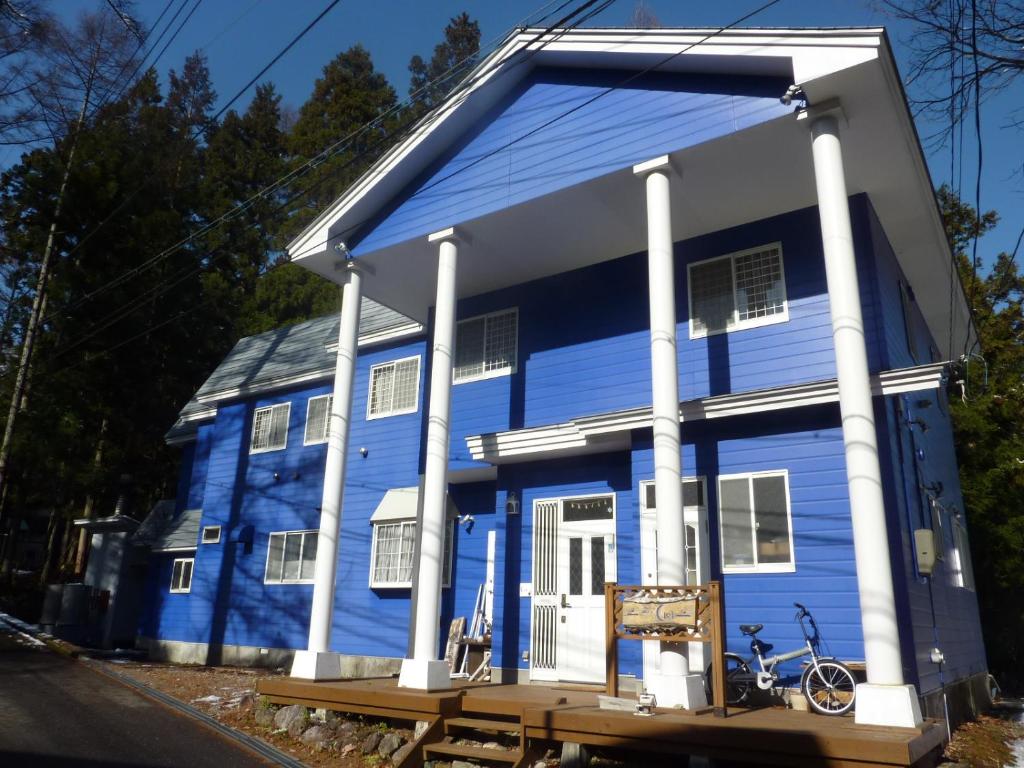 a blue house with a bench in front of it at Pension Ciel in Hakuba