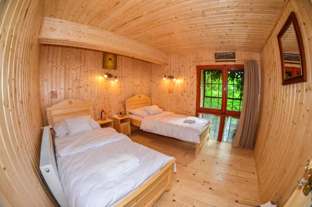 two beds in a room with wooden walls at Malom Apartman 2 in Derekegyház