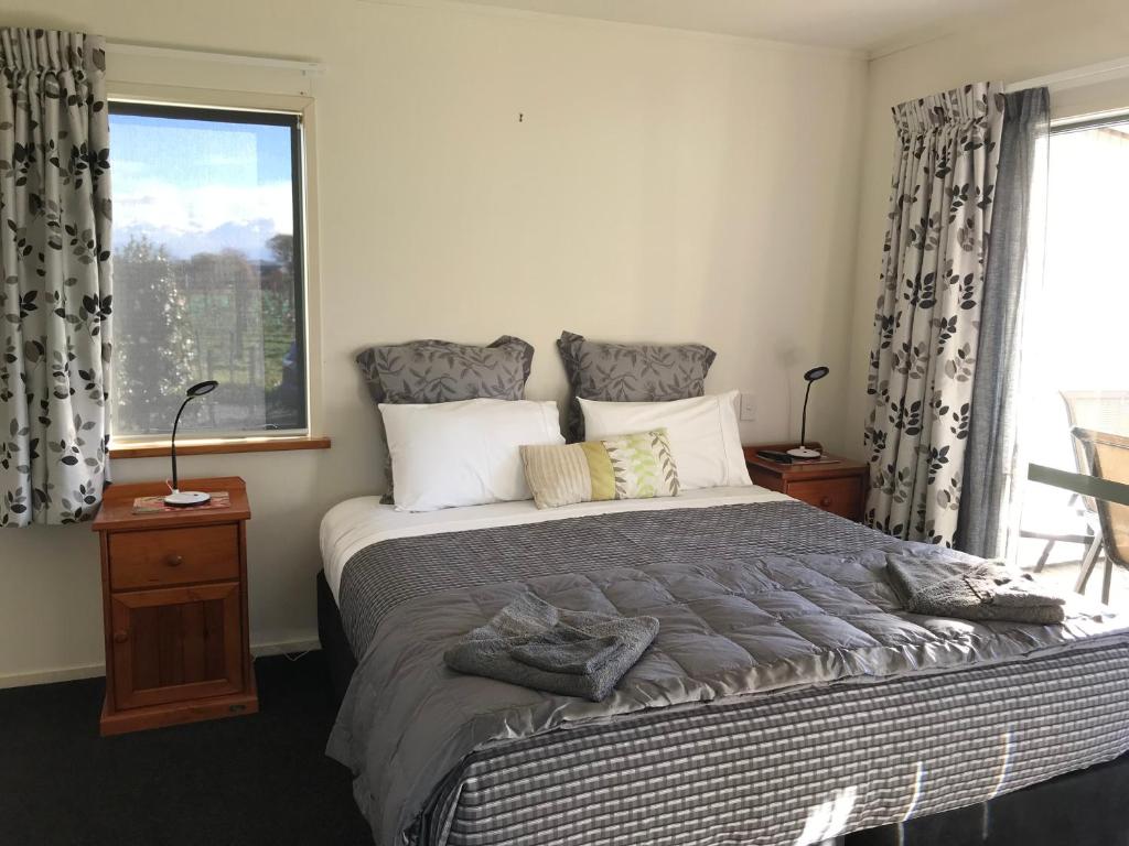 a bedroom with a large bed with a window at Bluebell Lodge and Cottage in Havelock North