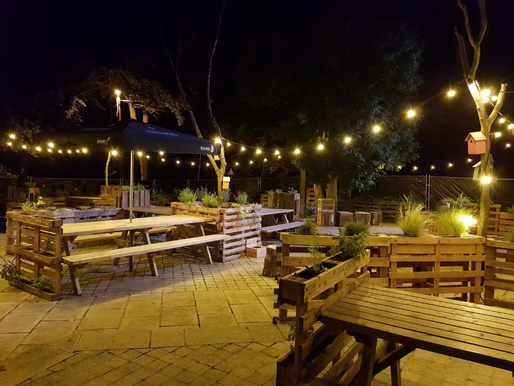a patio with wooden benches and lights at night at bosbAAr in Kluisbergen