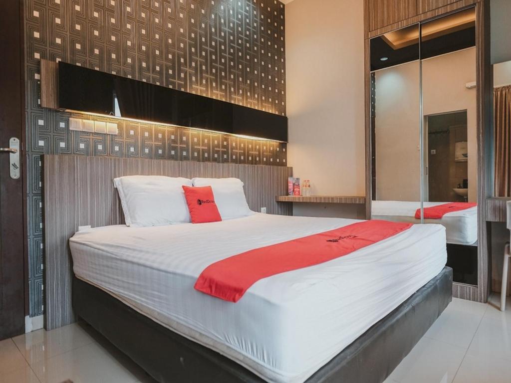 a bedroom with a large white bed with a red blanket at RedDoorz @ Jamin Ginting Medan in Medan